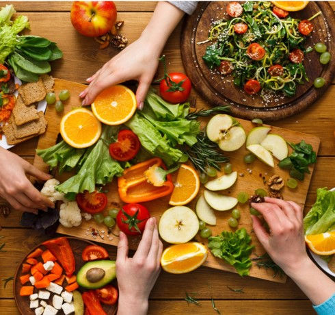 colorful fruits and vegetables to show prebiotic foods and fiber that feeds gut bacteria and also good for microbiome. oranges, apples, bell peppers, avocado, green leafy vegetables are amongst the spread of plant based food.